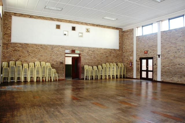 Spacious meeting room with stacked chairs, ideal for workshops and community events.