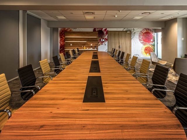 Modern conference room 1.4 at CTICC with a large wooden table, ideal for corporate meetings.