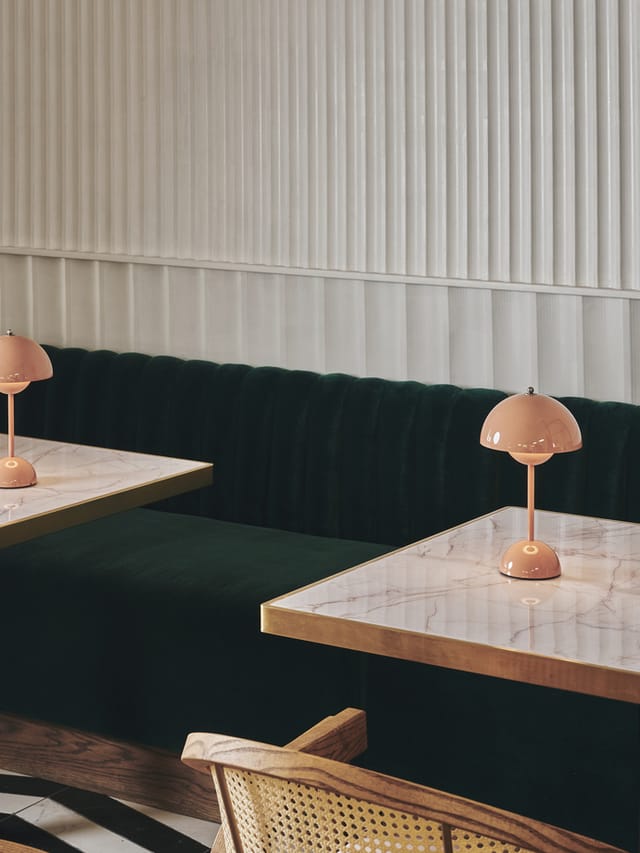 "Stylish meeting space with marble tables and green seating for networking events."