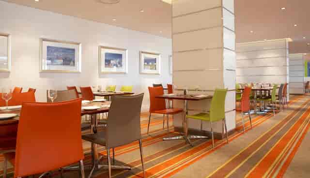 Modern dining area with vibrant orange and green chairs, ideal for networking events.