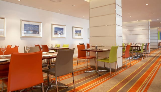 Modern dining area with vibrant orange and green chairs, ideal for networking events.