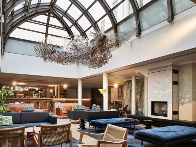 Modern hotel lobby with glass ceiling, ideal for networking events and gatherings.