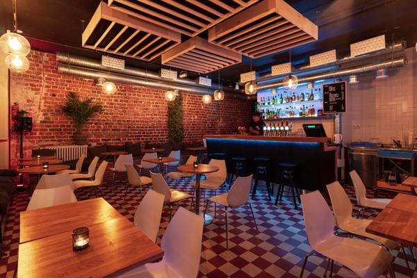 Modern cocktail bar with exposed brick in Pizzeria Via Tribunali, ideal for events.