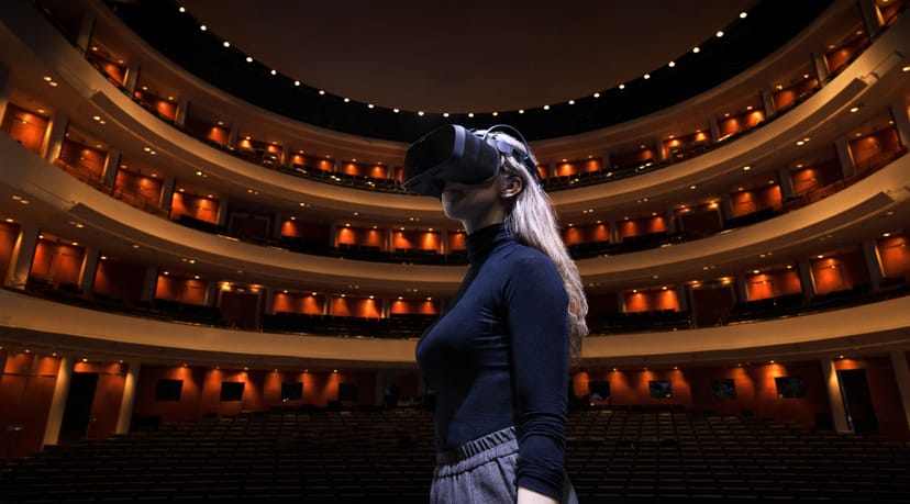 Woman with VR headset in Finnish National Opera theater for innovative event planning.
