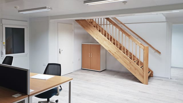 Modern minimalist office in HUONE Helsinki with wooden staircase, perfect for workshops.