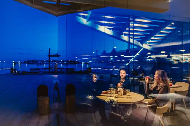 Stylish waterfront bar gathering with modern architecture for social events.