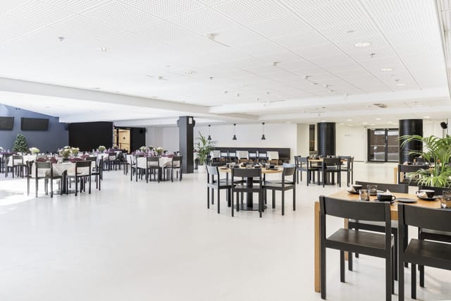 Spacious modern meeting venue with elegant dining setup for events in Ravintolasali.