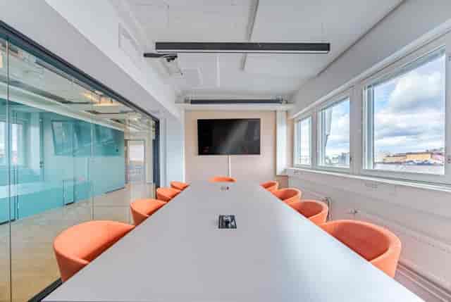 Modern conference room with white table, orange chairs for meetings and workshops.