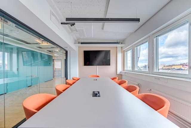 Modern conference room with white table, orange chairs for meetings and workshops.