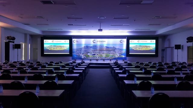 Conference setup at V&A Waterfront with organized tables, chairs, and presentation screens.