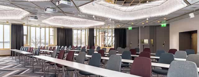 Modern Hilton Helsinki Strand ballroom for conferences with stylish furnishings and natural light.