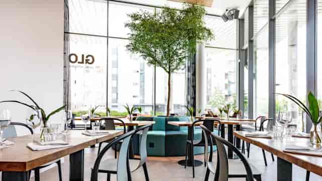 Modern restaurant with wooden tables, ideal for events and gatherings at GLO Hotels.