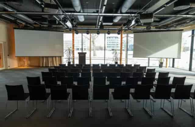Conference room in Little Finlandia, featuring black chairs and projector screens.