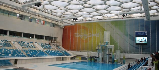 Modern Water Cube arena with hexagonal ceiling for swimming and entertainment events.