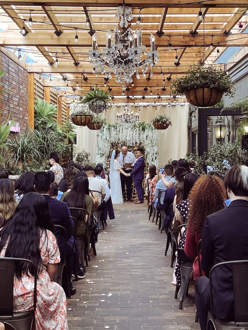 Elegant wedding ceremony at Angelicas with floral altar and lush greenery.