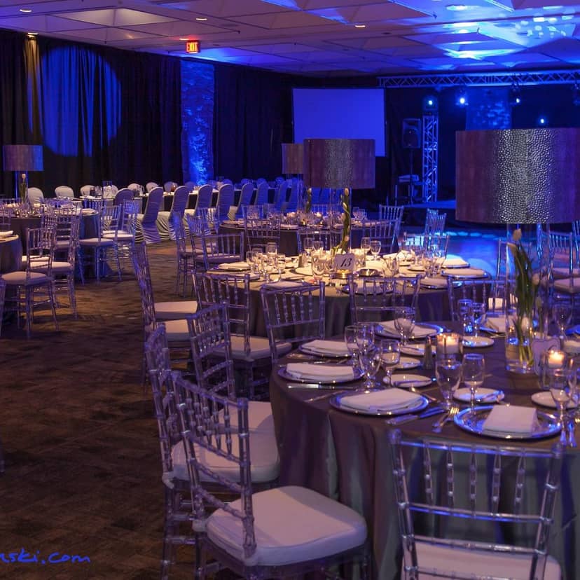 Elegant event space with round tables and blue lighting for upscale dinners and galas.