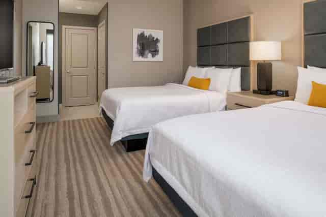 "Modern hotel room with two beds at Homewood Suites, ideal for corporate retreats."