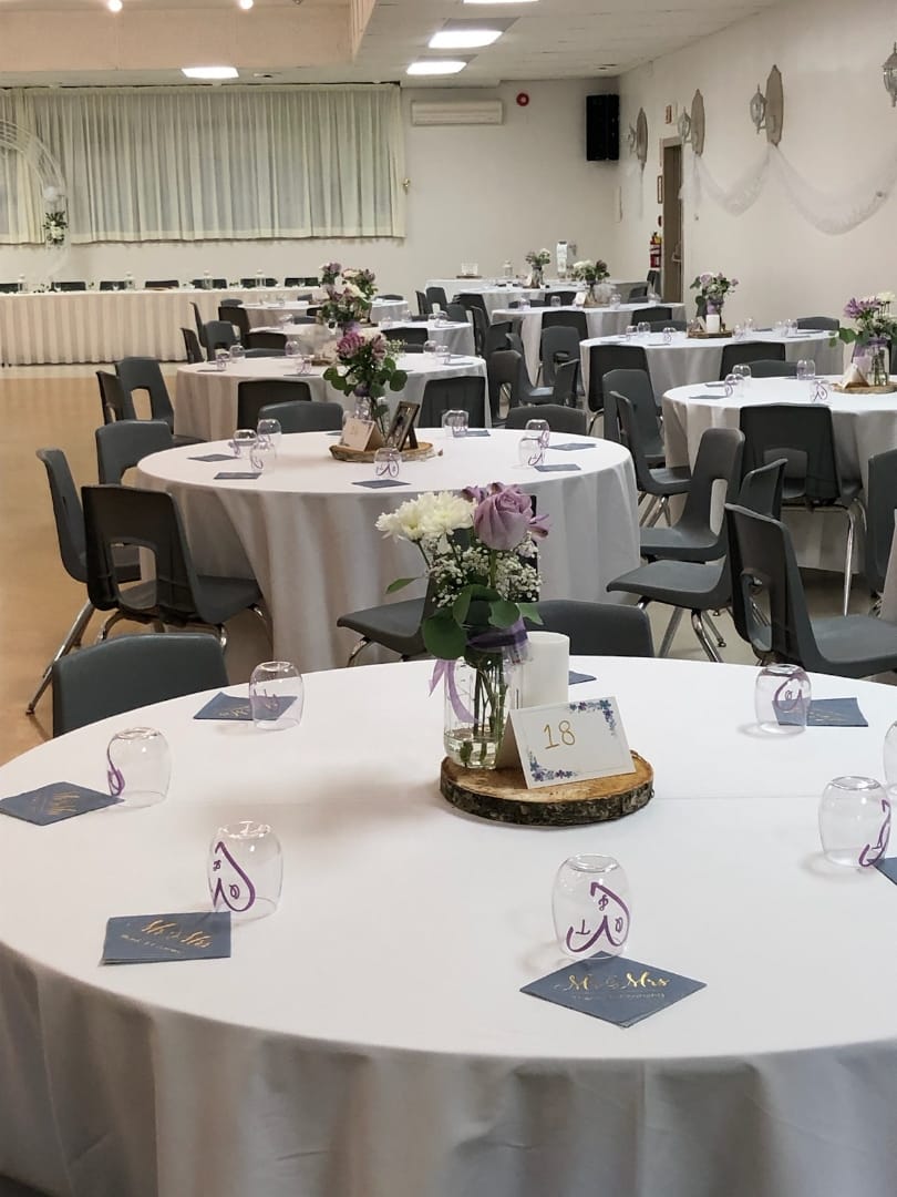 Elegant round tables with floral centerpieces at Belleville Fish and Game Club event space.