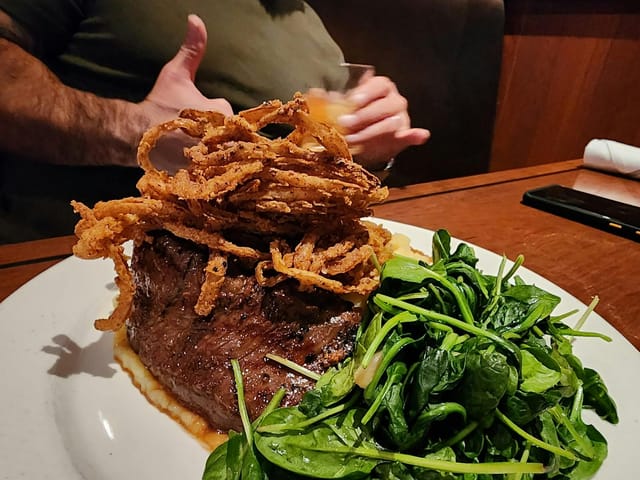 Plated steak dish with onion rings, ideal for corporate dinners and events in San Carlos.