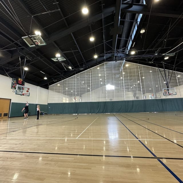 Indoor basketball gym with polished floor, ideal for corporate events and sports activities.