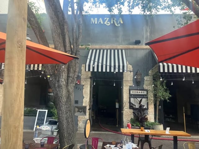 Charming outdoor dining area with striped awnings, perfect for casual gatherings and receptions.