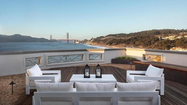 Outdoor patio at Cliff House with white lounge furniture and Golden Gate Bridge view for events.