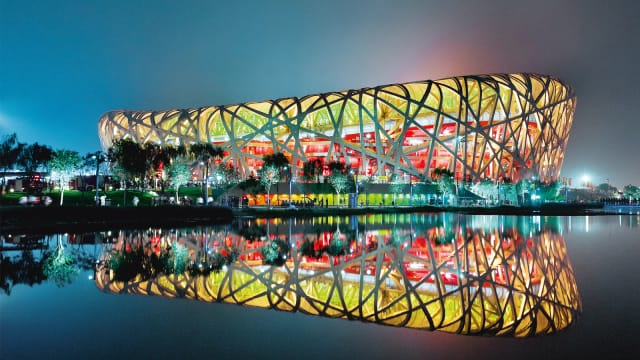 "Iconic Bird's Nest Stadium reflecting on water, ideal for concerts and sports events."