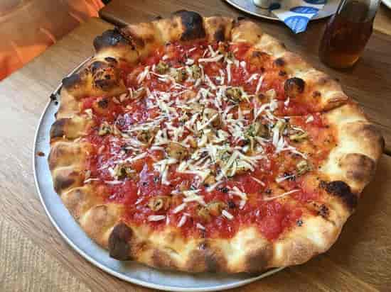 Freshly baked pizza with golden crust at Pizzeria Delfina, perfect for event catering.