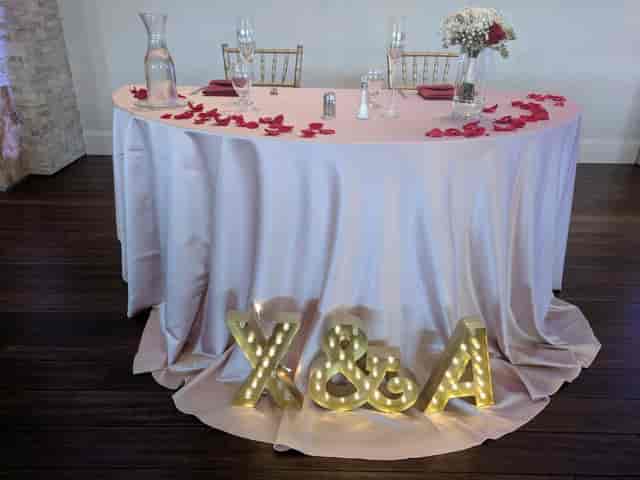 Elegant head table adorned with rose petals in Fairview Crystal Springs' Crystal Ball Room.