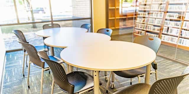 Well-lit meeting room with white tables and ergonomic chairs for productive collaboration.
