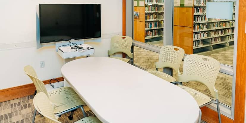 Small meeting room in Redwood City Library with oval table, ideal for workshops and presentations.