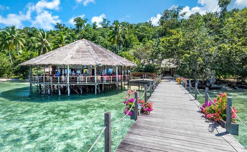 Waterside dining area with thatched roof, perfect for retreats and events in Raja Ampat.