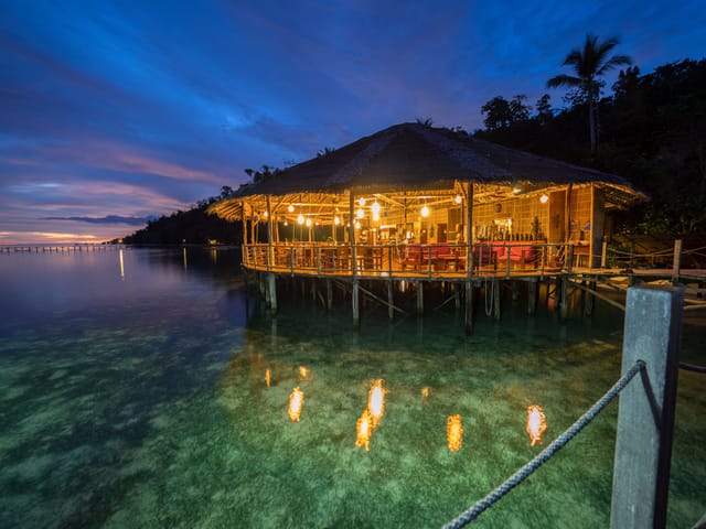 Dining area with bamboo structure over calm waters for corporate retreats in Raja Ampat.