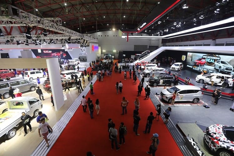 Jakarta International Expo automotive exhibition with modern and classic cars on a red carpet.
