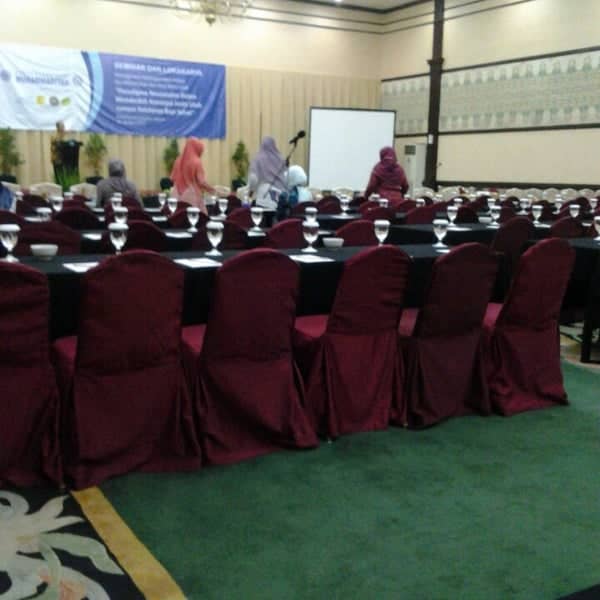 Ballroom conference setup at Hotel Grand Cempaka with elegant tables and burgundy chairs.