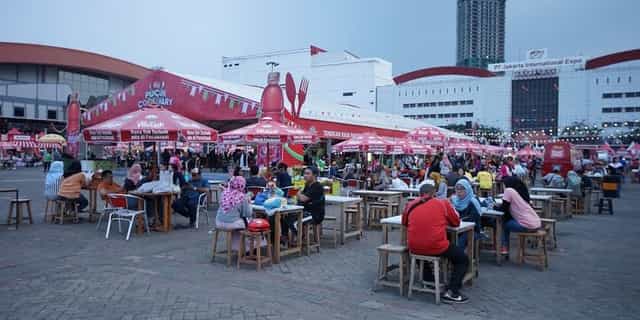 Lively Jakarta International Expo Hall B with vibrant umbrellas at a food festival.