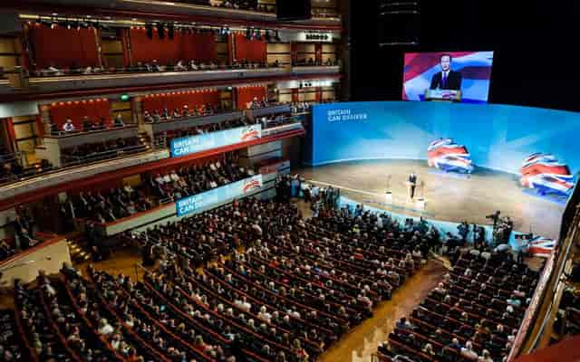Justham Family Room auditorium during a conference with attentive audience and vibrant branding.