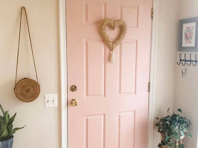 Inviting entryway with pink door and heart wreath for charming event atmosphere.