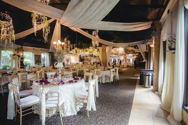 Elegant corporate event venue with draped fabric and floral arrangements for weddings.