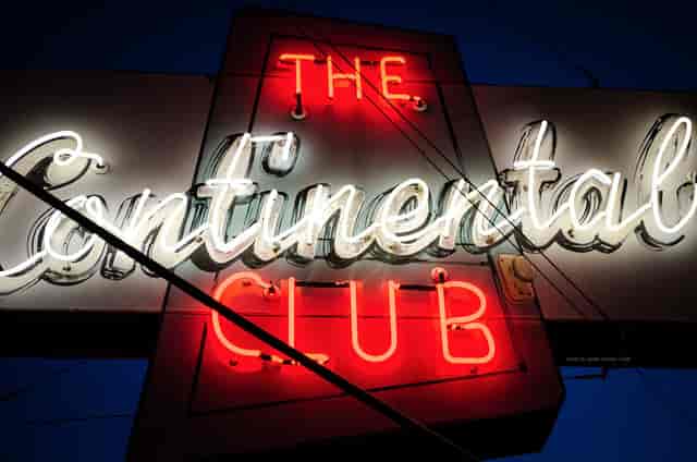 Vibrant neon sign at Shoeshine Charley's Big Top Lounge for live music and events.