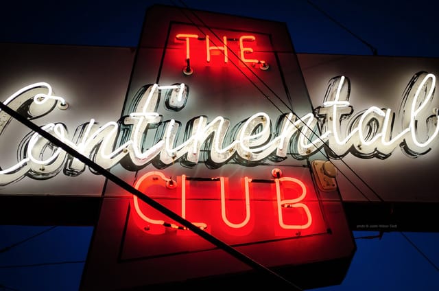 Vibrant neon sign at Shoeshine Charley's Big Top Lounge for live music and events.