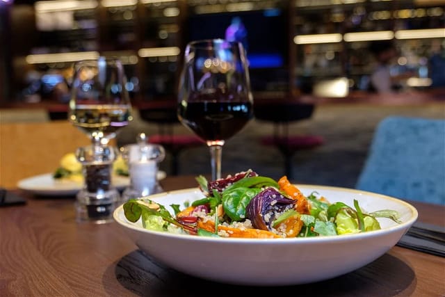 Upscale dining table with vibrant salad and wine at 1857 Sports Lounge, perfect for events.