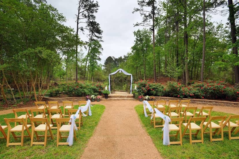 Outdoor wedding venue with wooden chairs and a white fabric arch at Artesian Lakes.