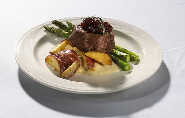 Plated beef dish with berry sauce, perfect for events and catering at The Pinnacle Center.