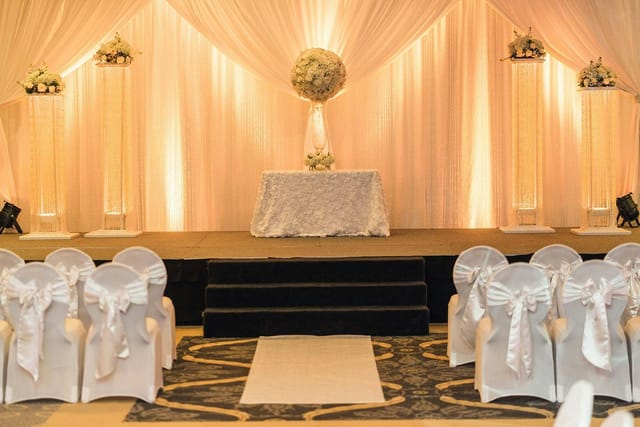 Elegant wedding stage at HORIZONS Conference Center with floral decor and satin sashes.