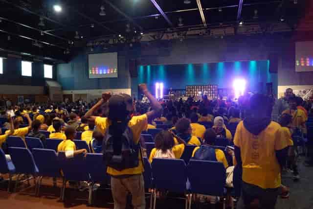 Vibrant banquet hall at KBC Houston, packed audience in yellow shirts for a conference.