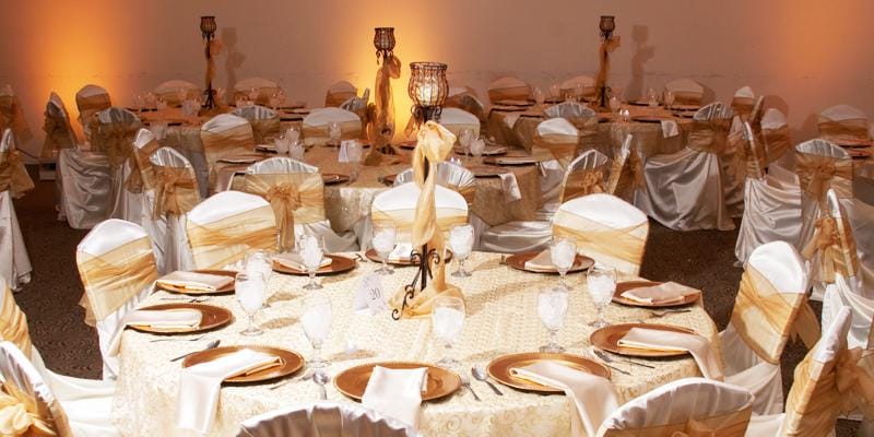 Elegant banquet hall with gold and white decor, ideal for weddings and corporate events.