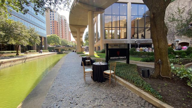 Elegant outdoor patio with tables by waterway for upscale events and networking.