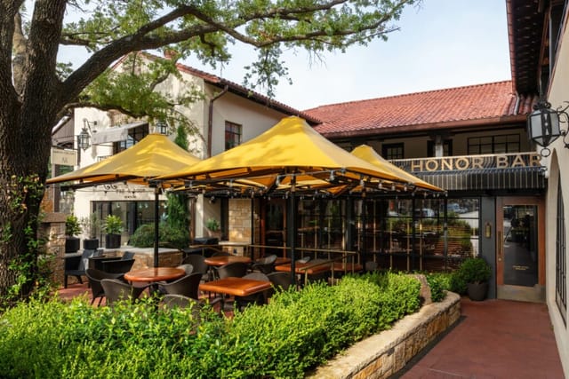 Charming outdoor patio at The Highland Dallas for casual meetings with vibrant yellow canopies.