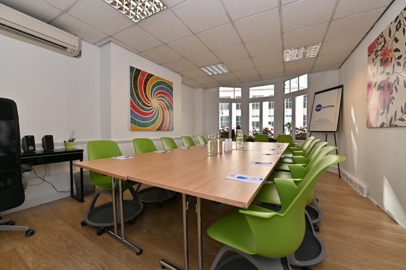 Modern meeting room in Oslo with wooden table and green chairs for collaborative events.